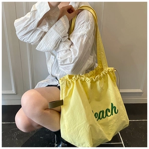 Detail of yellow nylon tote bag with green letter print and drawstring closure design