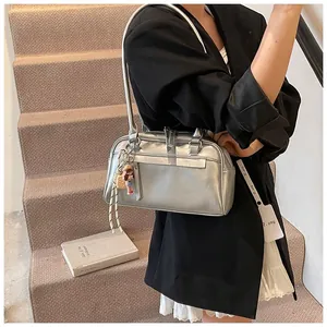Silver metallic Boston bag with slim handles and doll charm worn with a black oversized blazer