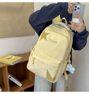 Détail du sac à dos en nylon jaune avec patchs étoiles et broderie S-J-N élégante
