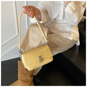 Detail view of light yellow oily leather baguette bag with silver buckle on a model