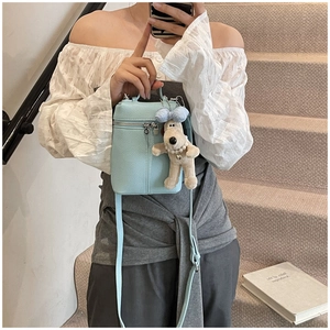 Close-up of baby blue lychee pattern leather bucket bag with dog plush pendant
