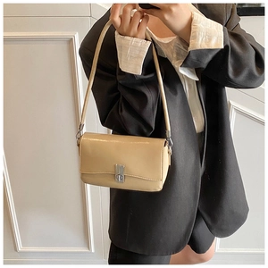 Detail showing the beige glossy leather bag texture and silver metal rotating clasp lock