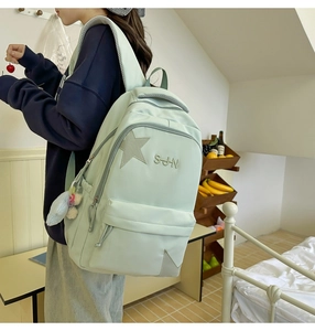 Vue détaillée du sac à dos scolaire vert clair avec écusson étoile et pendentif peluche