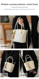 Detail view of white mini bucket bag featuring gold hardware and woven fringe charm