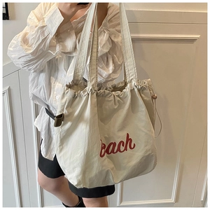 Detail view of large canvas tote bag with red Beach script and drawstring closure