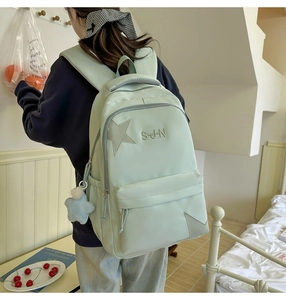 Détail du sac à dos en nylon vert clair avec broderie étoile et accessoire en peluche étoile