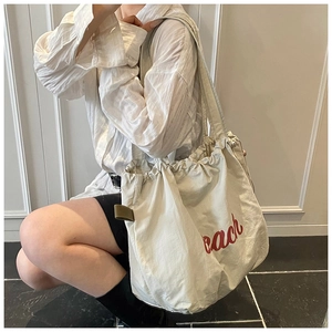 Detail of cream canvas tote bag with red beach lettering and drawstring closure