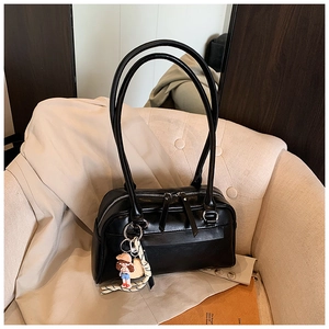 Detailed shot of a black vintage Boston bag featuring a cute doll charm and striped scarf