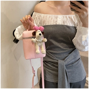 Detail view of pink litchi grain leather crossbody bag with a sweet plush charm