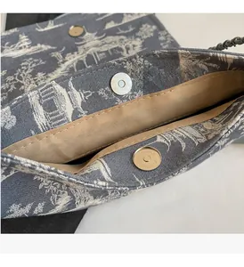 Close-up of golden magnetic buckle and chain strap on landscape pattern tote bag