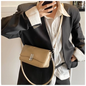Close-up of khaki oil wax leather crossbody bag worn over a black blazer and white shirt