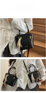 Detail of black PU bucket bag showing top handle, gold hardware, and silk scarf accents
