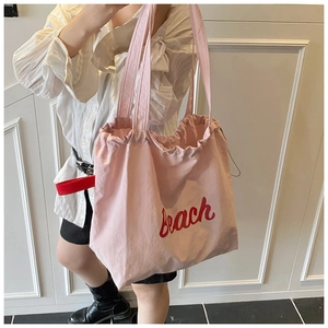 Detail of light pink canvas tote bag with red beach print and drawstring closure