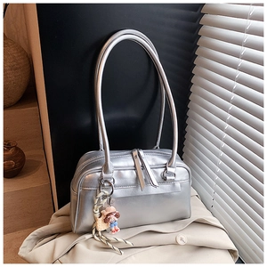 Close-up of metallic silver Boston bag with sleek dual handles and stylish doll pendant