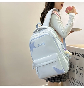 Détail d'un sac à dos en nylon bleu clair avec des étoiles et un pendentif en peluche