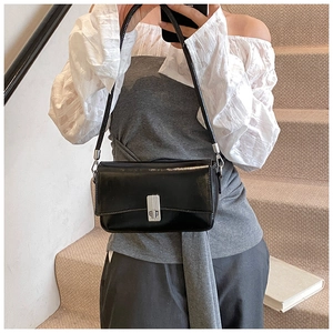 Detail of black glossy leather shoulder bag with rectangular silver metal clasp lock