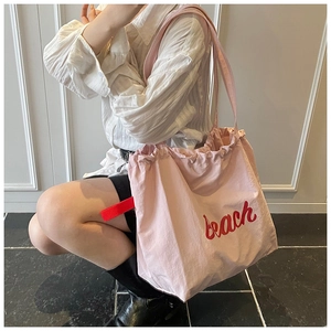 Pink canvas tote bag featuring large red beach text and decorative side ribbon detail