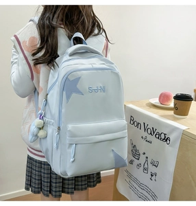 Détail d'un sac à dos en toile bleu clair avec broderie étoile et pendentif blanc doux