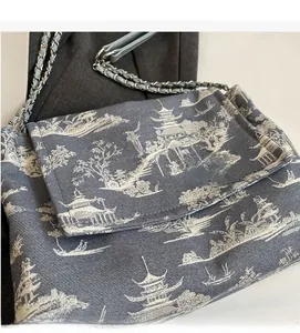 Detail of grey-blue canvas tote bag featuring landscape print and silver metal chain