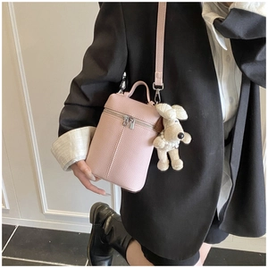Pink cylinder crossbody bag with litchi texture and a white poodle plush charm