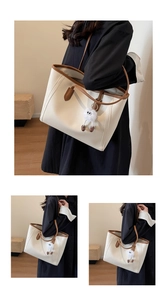 Detail view of large faux leather tote bag with brown trim and cute plush charm pendant