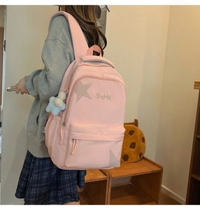 Sac à dos rose avec écusson étoile et charm en peluche dans un décor de vie quotidien