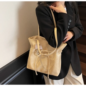Dettaglio della borsa tote in pelle gialla con fiocco a scacchi e ciondolo di perle