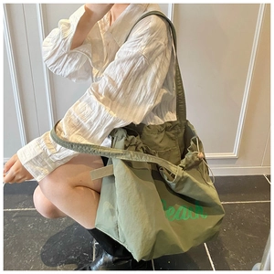 Detailed view of the grass green nylon drawstring tote bag with Beach print lettering