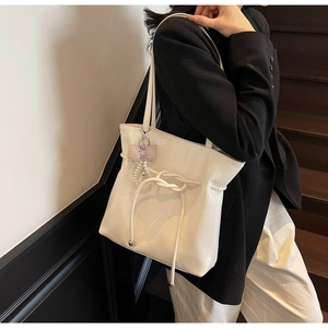 Dettaglio della borsa tote in pelle cerata crema con nodi a coulisse e ciondolo di perle