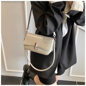 Detail of a creamy white rectangle shoulder bag with a striped silver metal buckle
