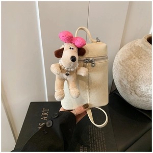 Detail of off-white lychee texture mini bucket bag with cute plush puppy charm decoration