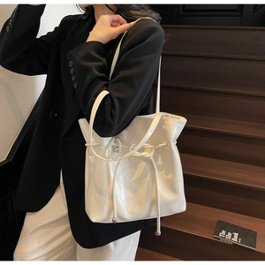 Vista dettagliata della borsa tote bianco crema lucida con elegante ciondolo di perle