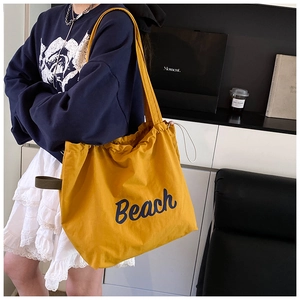 Detail of yellow canvas tote bag with Beach print, drawstring closure and wide strap