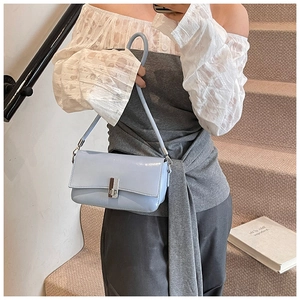 Detail of light blue glossy leather shoulder bag with elegant silver metallic buckle closure