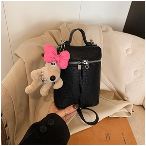 Detail of black lychee grain cylinder bag with pink bow puppy plush pendant accessory