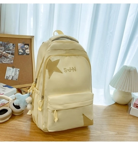 Détail d'un sac à dos en nylon crème avec broderie étoilée et breloque en peluche douce