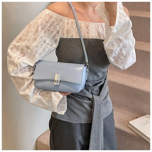 Detailed view of light blue glossy leather square bag with silver metal lock and strap