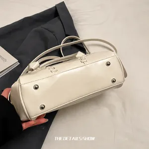 Detail view of cream bowling bag with silver bottom studs and woven stitching