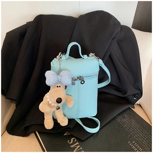 Detail of light blue lychee pattern mini bag with cute puppy plush charm and silver zipper