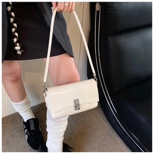 Detailed view of a white leather crossbody bag with vertical striped metal buckle