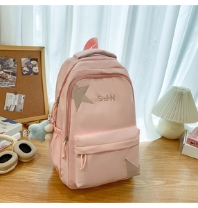 Détail du sac à dos en nylon rose avec patch étoile, broderie et pendentif étoile bleue