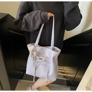 Dettaglio della borsa tote in ecopelle lilla con fiocco a scacchi e ciondolo di perla