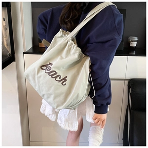 Detail of the drawstring closure and Beach letter print on the beige canvas tote bag