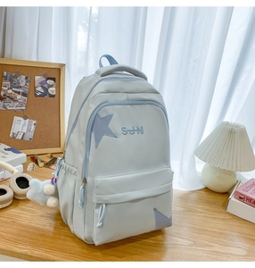Détail d'un sac à dos en nylon bleu clair avec écusson étoile et pendentif en peluche