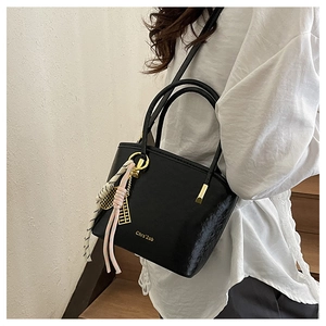 Detail of black PU bucket bag with striped silk scarf and golden abacus charm