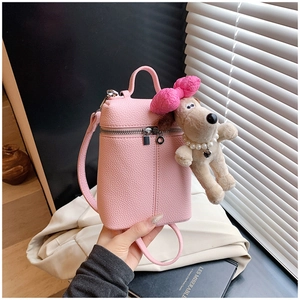 Close-up of pink litchi grain bucket bag with a cute puppy plush charm and silver zipper