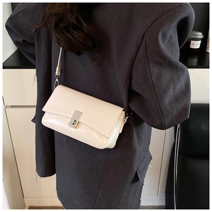 Detail of cream oil wax leather crossbody bag with silver buckle on a shoulder strap