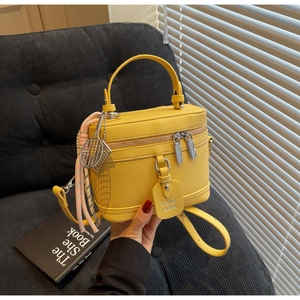 Détail du sac boîte jaune vif en cuir grainé avec fermeture éclair et breloque tennis