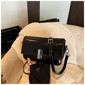 Detail of a black oil wax leather crossbody bag featuring a silver metal lock and strap