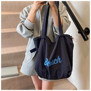 Detail of navy blue oversized tote bag with white Beach print and drawstring closure